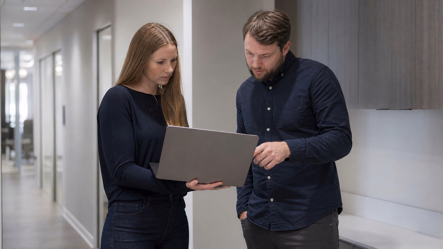 INFORMAL HUDDLE An IT professional two people standing and talking near a ki