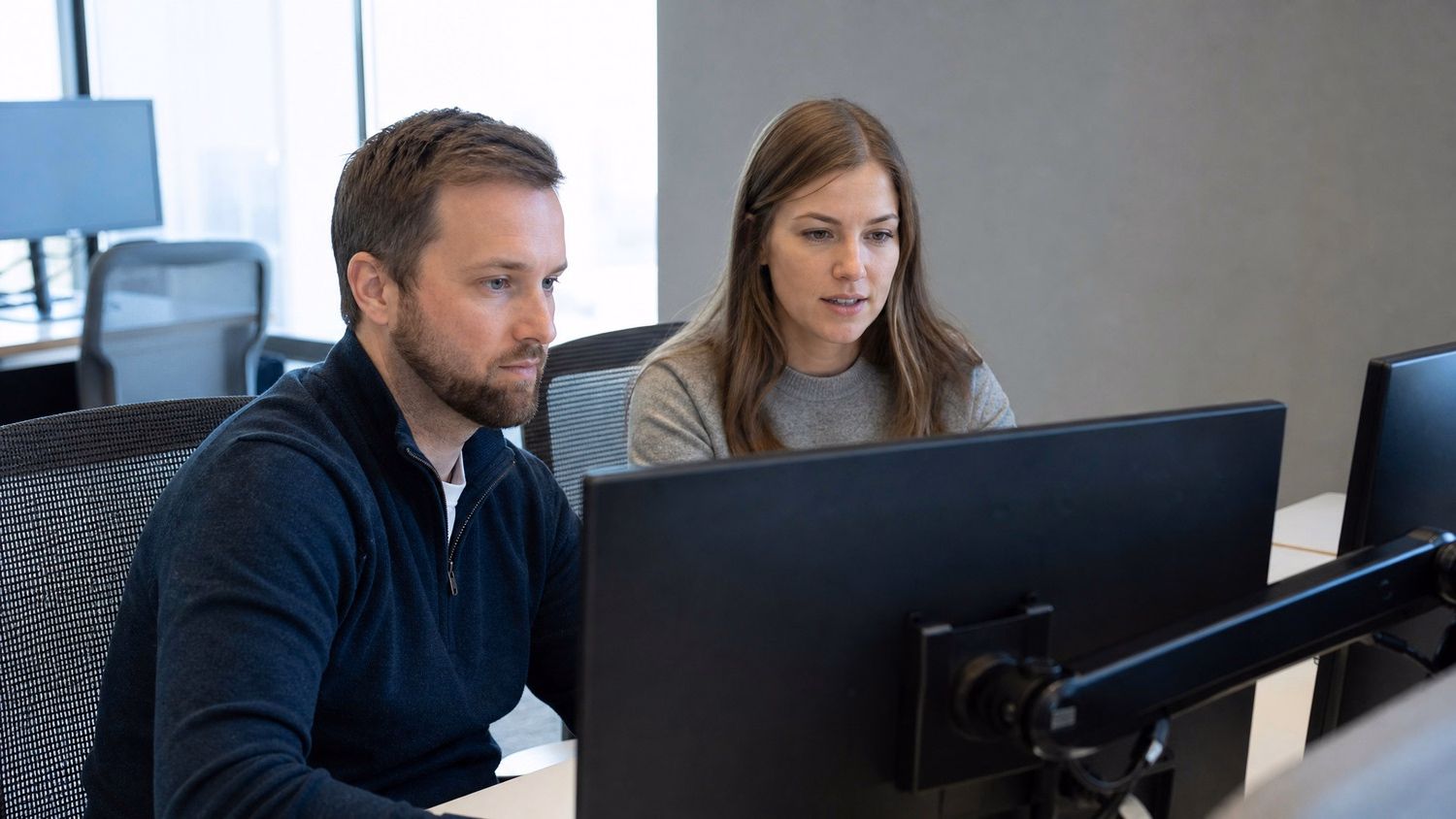SIDE-BY-SIDE PAIR An IT professional  two people seated side by side reviewin