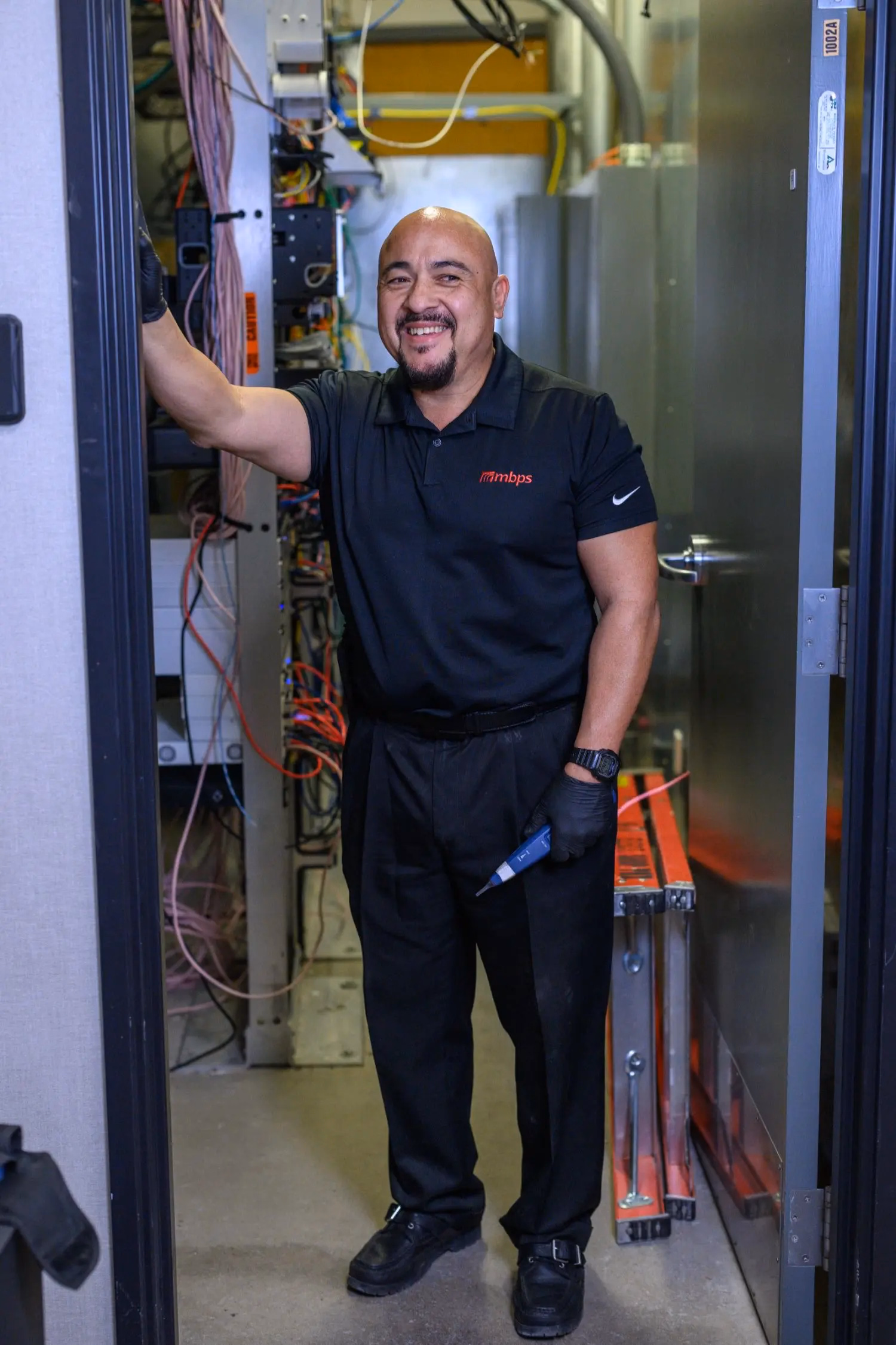 MBPS technician standing beside an open network cabinet