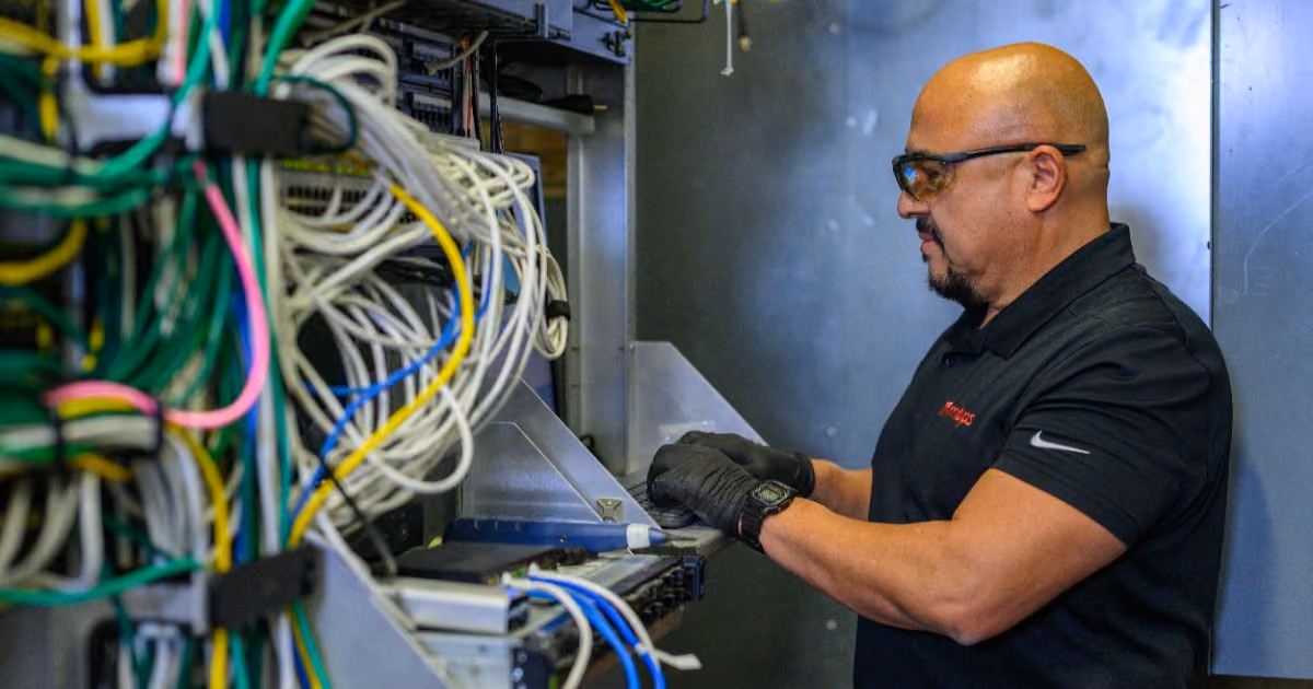 MBPS technician working on a network cabinet full of cabling