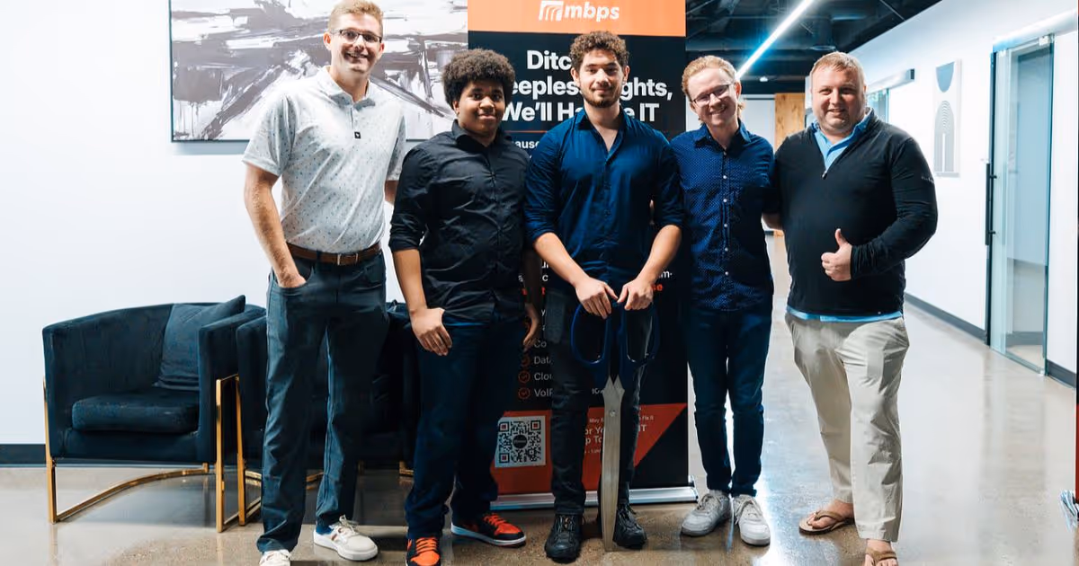 MBPS team standing together in the office in front of a marketing display