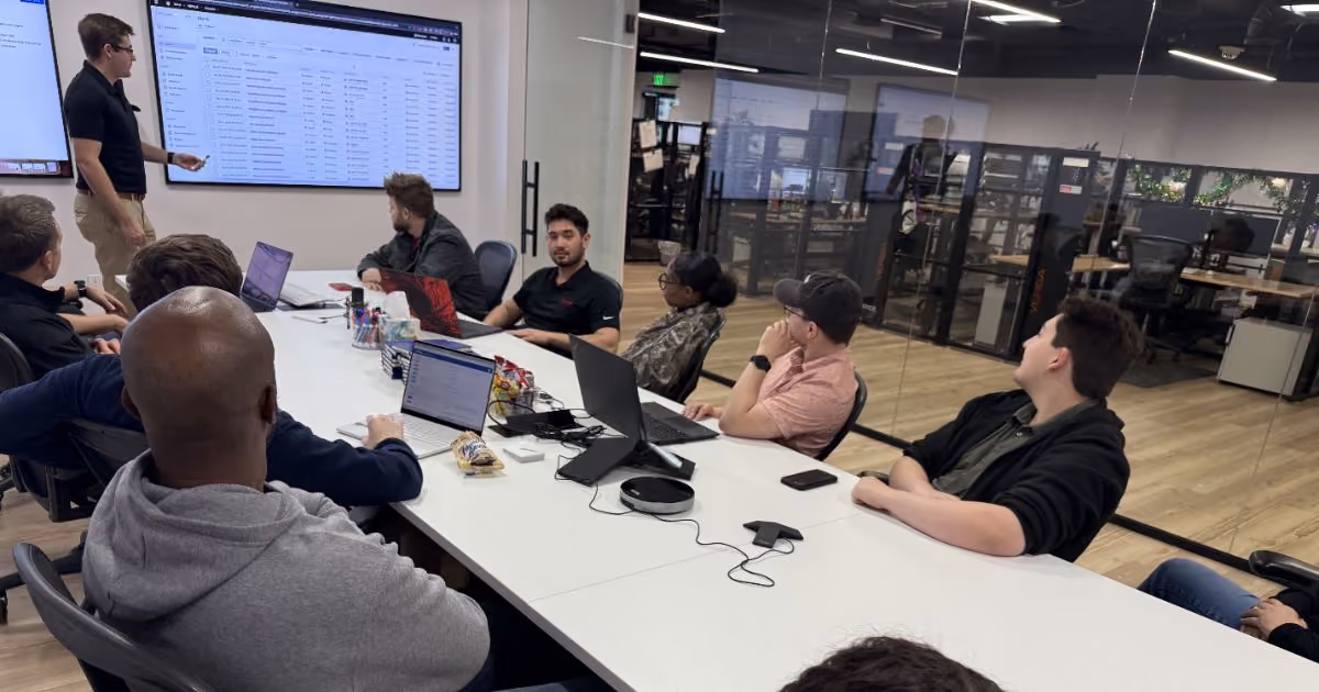 MBPS staff seated around a conference table facing wall screens