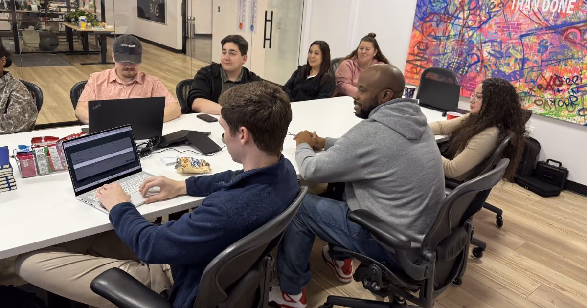 MBPS team meeting around a table beneath a colorful mural