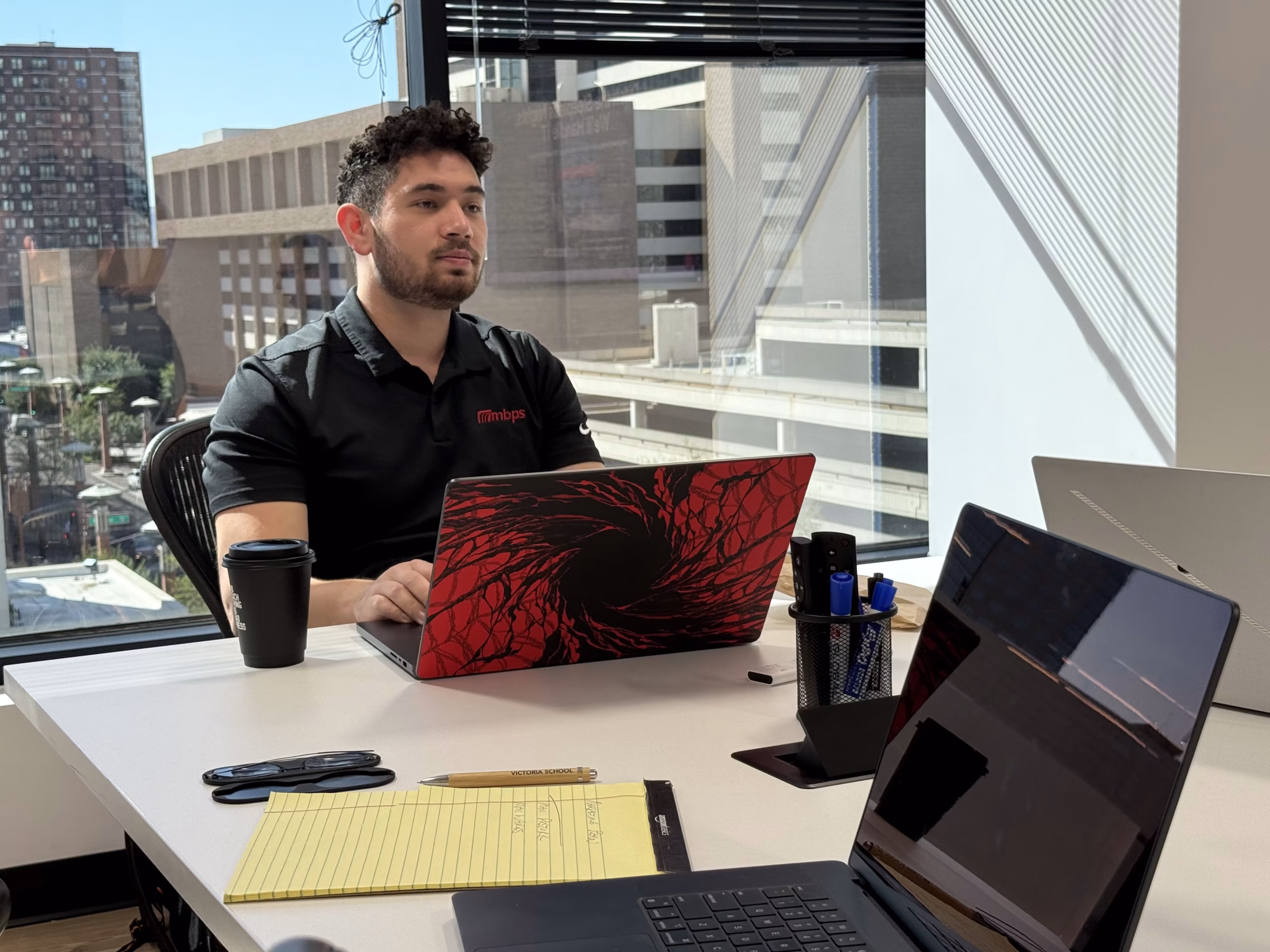 MBPS team member in a black polo working on a laptop in the Phoenix office