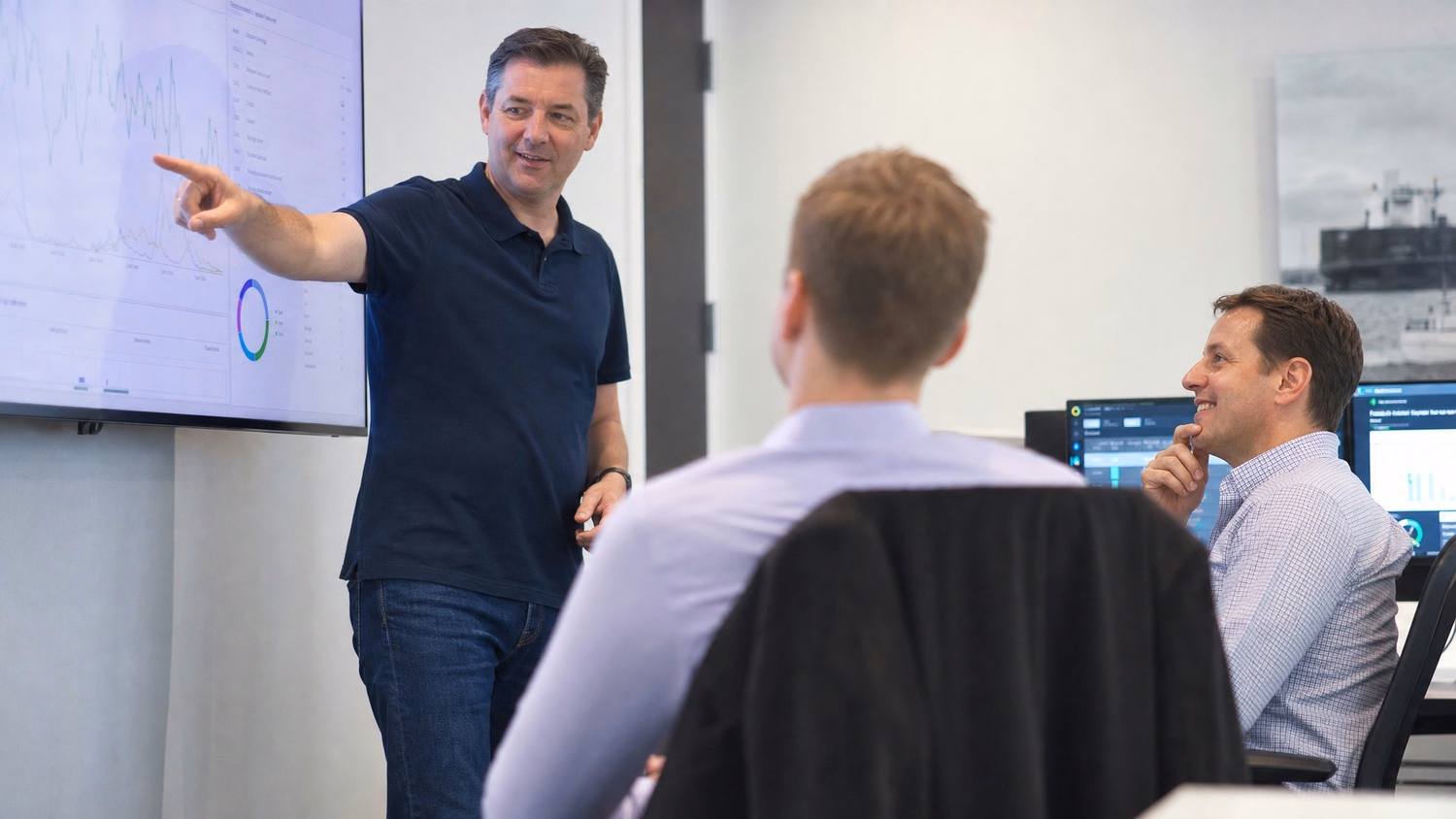 Man in polo points at graph on presentation screen